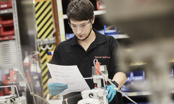 Technician in a lab referring to notes.